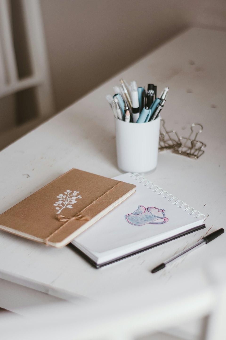Organized desk with sketchpad, notebook, and pens.
