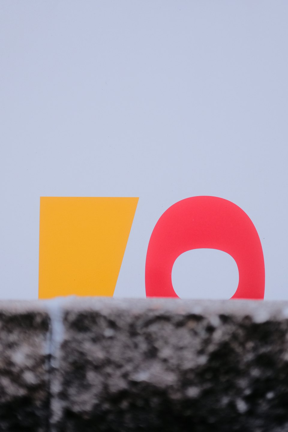 Yellow and red abstract graphic shapes on a grey wall.