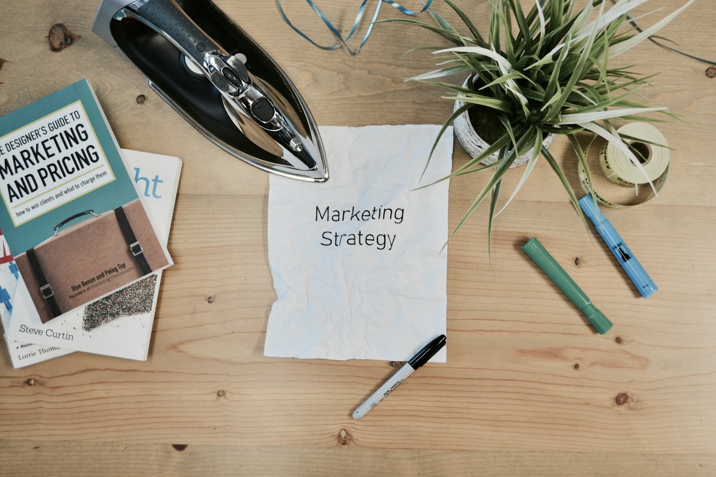 Wooden desk with marketing books and crumpled 'Marketing Strategy' paper.