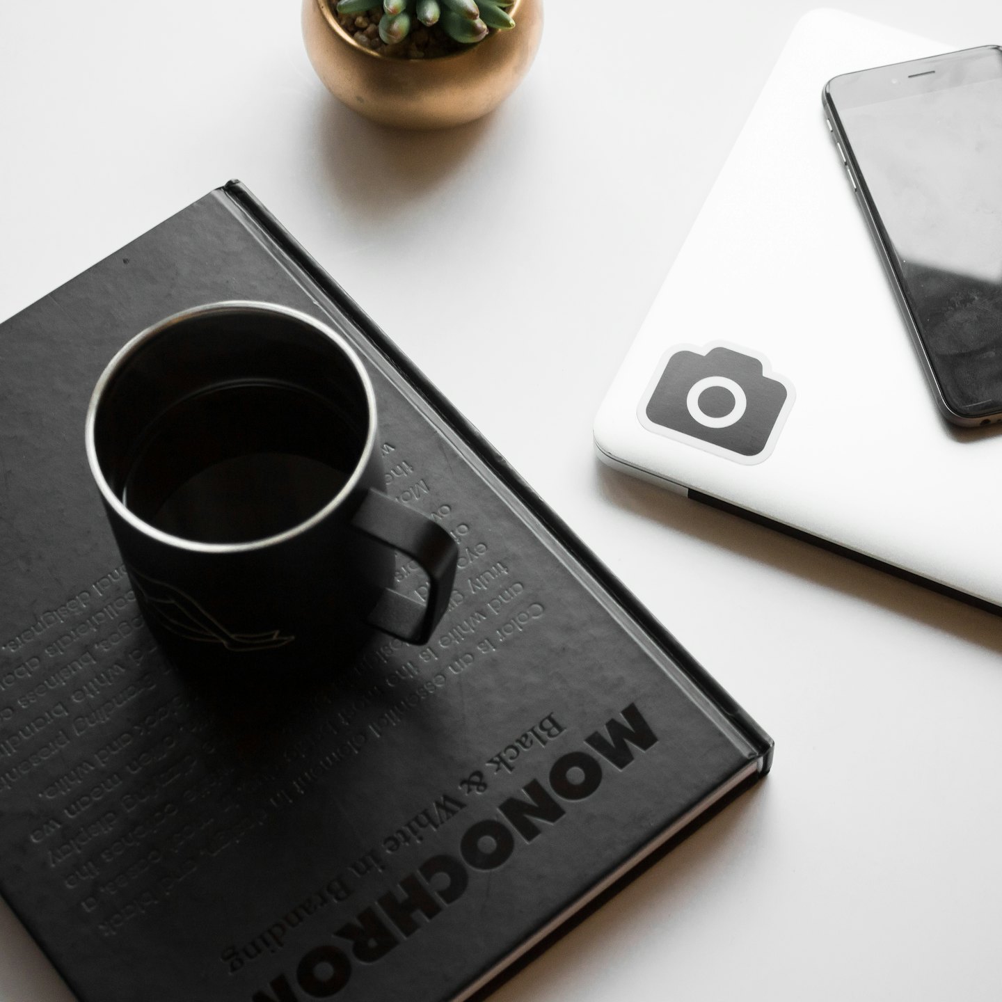 Desk items including a book, laptop, smartphone, and succulent plant.